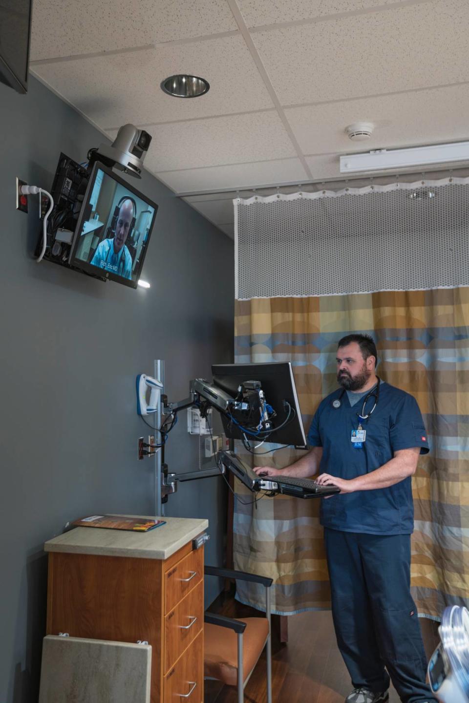 Josh Patterson, a registered nurse at St. Luke’s Health System, looks at a computer in a patient’s room in Nampa. Dr. Eric Rich appears on the other screen.