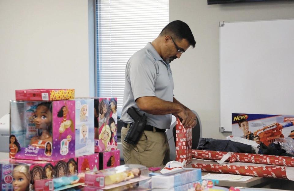 Port Orange police Officer Wayne Jean wraps toys and donations gifted to 'Cops for Christmas' initiative, Saturday, Dec. 11, 2021