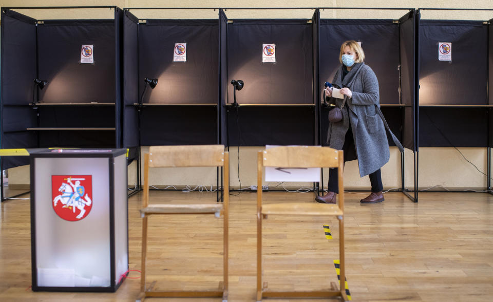 A local resident walks to cast a ballot at a polling station during the second round of a parliamentary election in Vilnius, Lithuania, Sunday, Oct. 25, 2020. Polls opened Sunday for the run-off of national election in Lithuania, where the vote is expected to bring about a change of government following the first round, held on Oct. 11, which gave the three opposition, center-right parties a combined lead. (AP Photo/Mindaugas Kulbis)