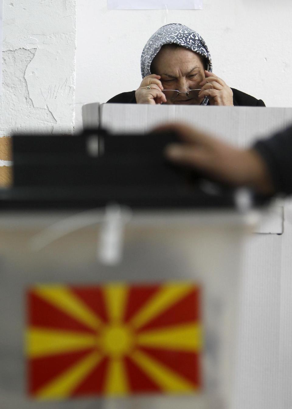 A woman puts on her glasses before voting at a polling station in village of Tearce, in northwestern Macedonia, on Sunday, Dec. 25, 2016. Authorities in Macedonia have ordered a Christmas Day rerun of a parliamentary election in one voting district - a decision that could threaten the slim majority of the long-governing conservatives. (AP Photo/Boris Grdanoski)