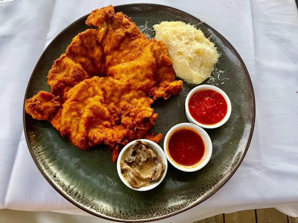 The Slough House Kitchen’s pork schnitzel is served with mashed potatoes and three side sauces.