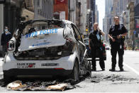 Officers stand guard beside a burned-out mini-New York Police Department vehicle, abandoned on Broadway in Lower Manhattan, Sunday, May 31, 2020, in New York, following a night of unrest and protests over the death of George Floyd, a black man who was in police custody in Minneapolis. Floyd died after being restrained by Minneapolis police officers on May 25. (AP Photo/Kathy Willens)