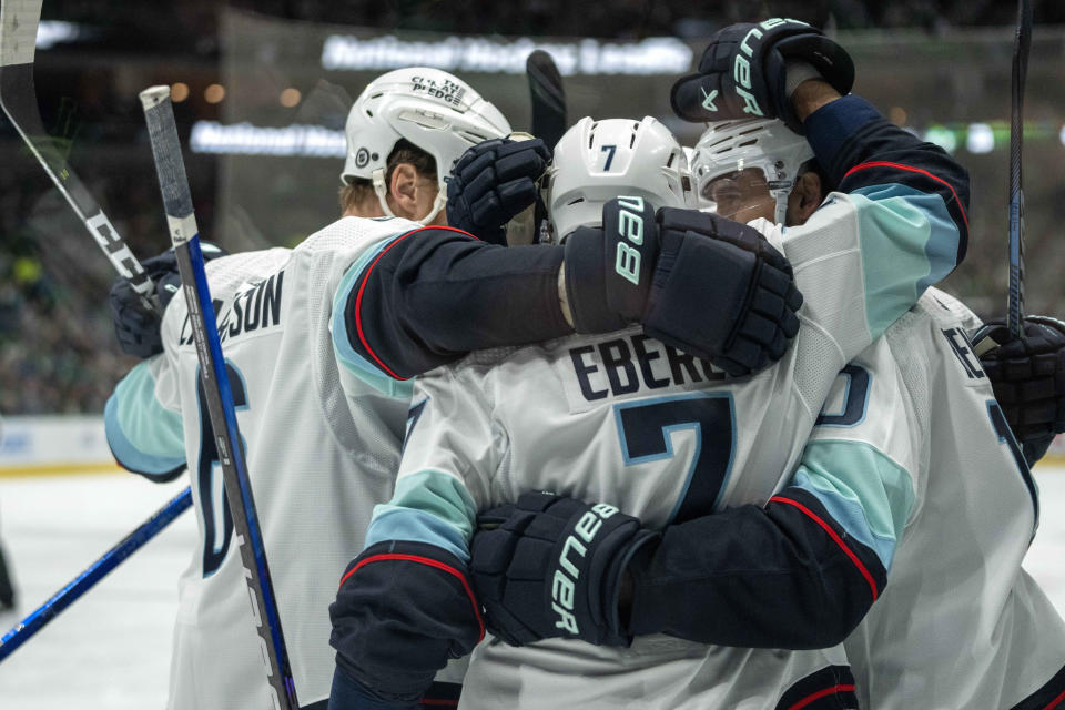 Seattle Kraken defenseman Adam Larsson (6), right wing Jordan Eberle (7) and center Matty Beniers, right, celebrate Beniers' goal during the second period of an NHL hockey game against the Dallas Stars Monday, Dec. 18, 2023, in Dallas. (AP Photo/Jeffrey McWhorter)