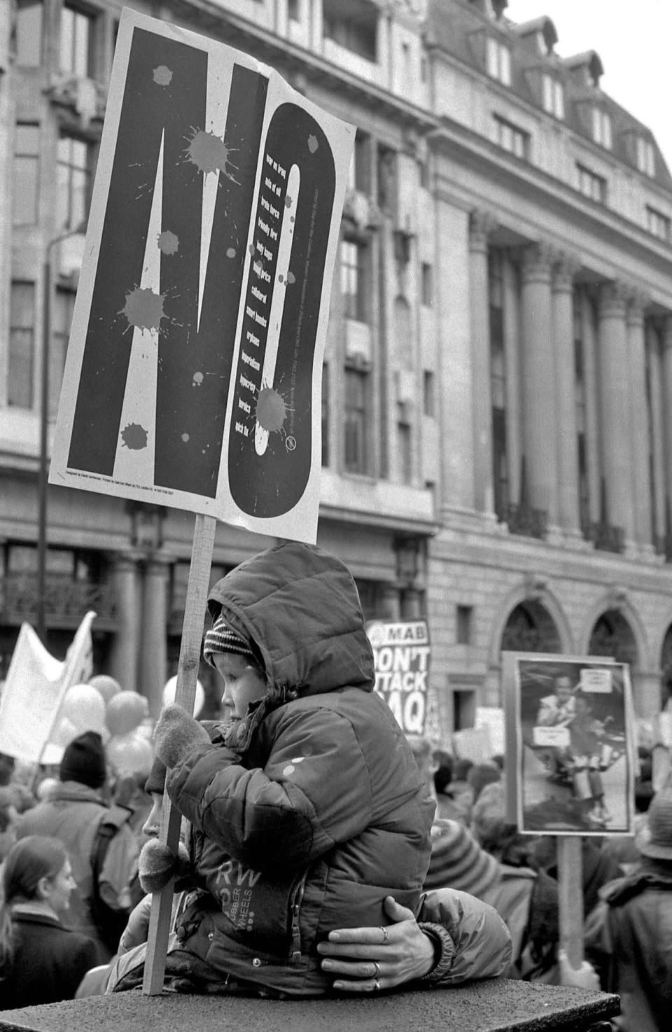 Young and old united: A child holds a sign while large groups of protesters march past