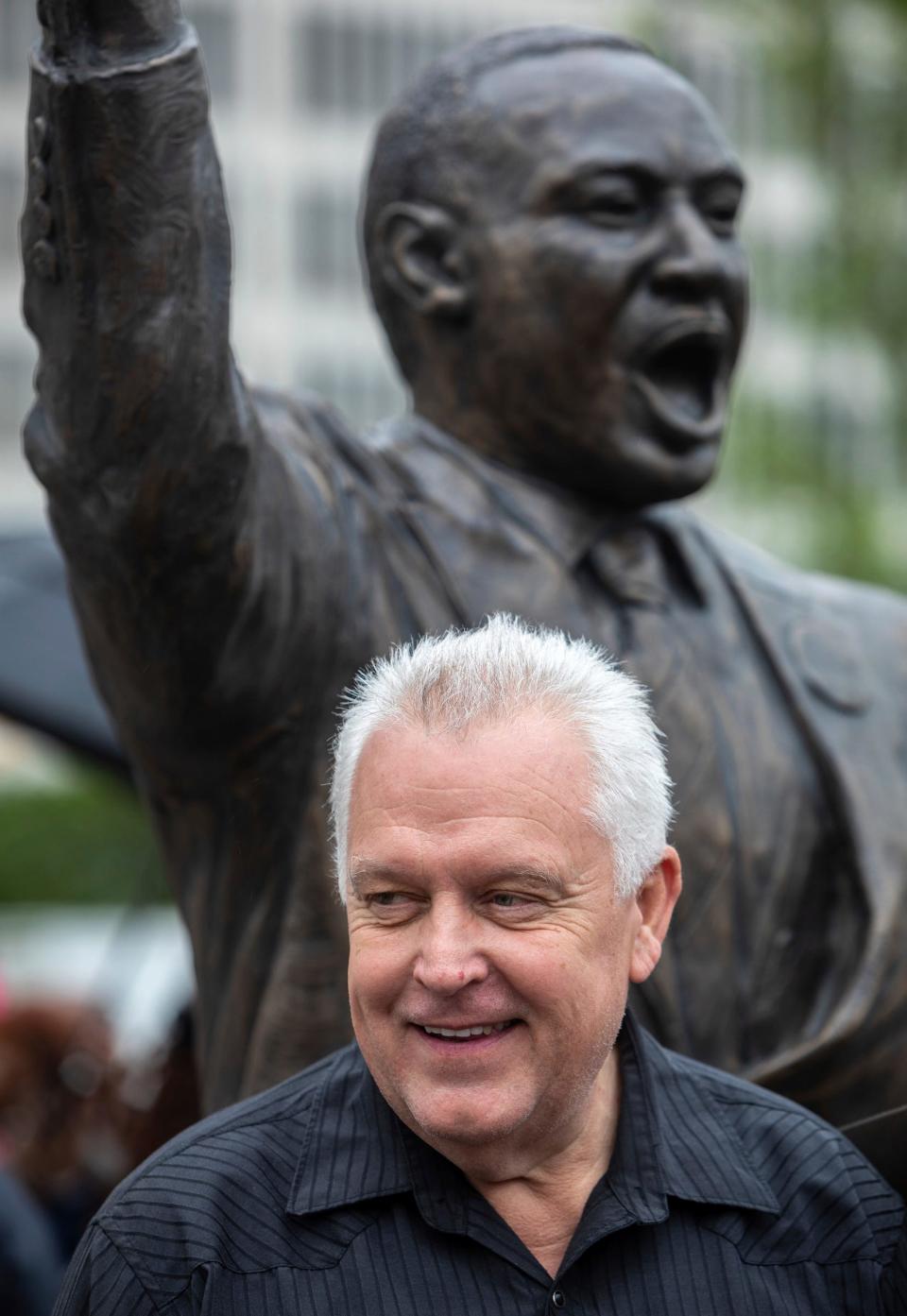 Artist Stan Watts smiles in front of the Martin Luther King Jr. statue at Hart Plaza in Detroit on Friday, June 23, 2023. 