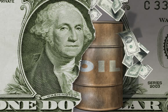 A barrel of oil coming through a dollar bill.