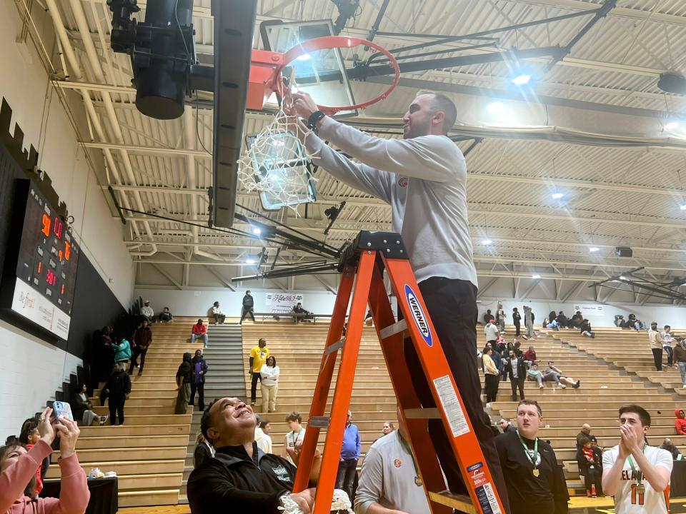 Delaware Hayes coach Adam Vincenzo finishes cutting down the net after the Pacers defeated Walnut Ridge 90-76 on Saturday to win their first district title since 1986.