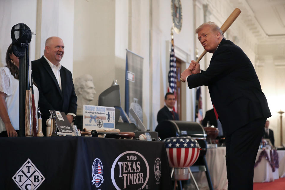 Donald Trump holds a baseball bat.