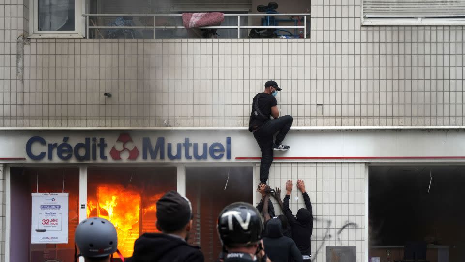 A protester climbs on a building during clashes that broke out in Nanterre. - Zakaria Abdelkafi/AFP/Getty Images