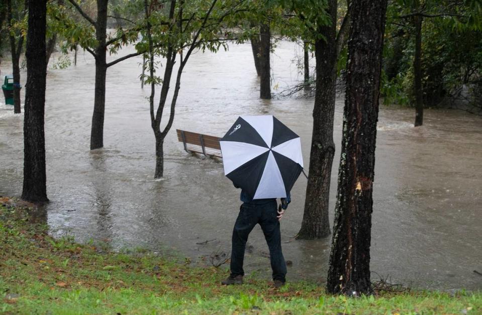 A onlooker stops at the Walnut Creek Greenway on Bragg Street in Raleigh as heavy rain pushes Walnut Creek from its banks flooding the greenway trail on Thursday, November 12, 2020.