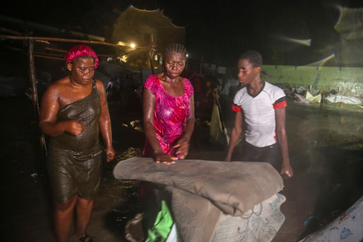 People affected by Saturday's earthquake stand under the rain of Tropical Depression Grace at a refugee camp in Les Cayes, Haiti, Monday, Aug. 16, 2021.