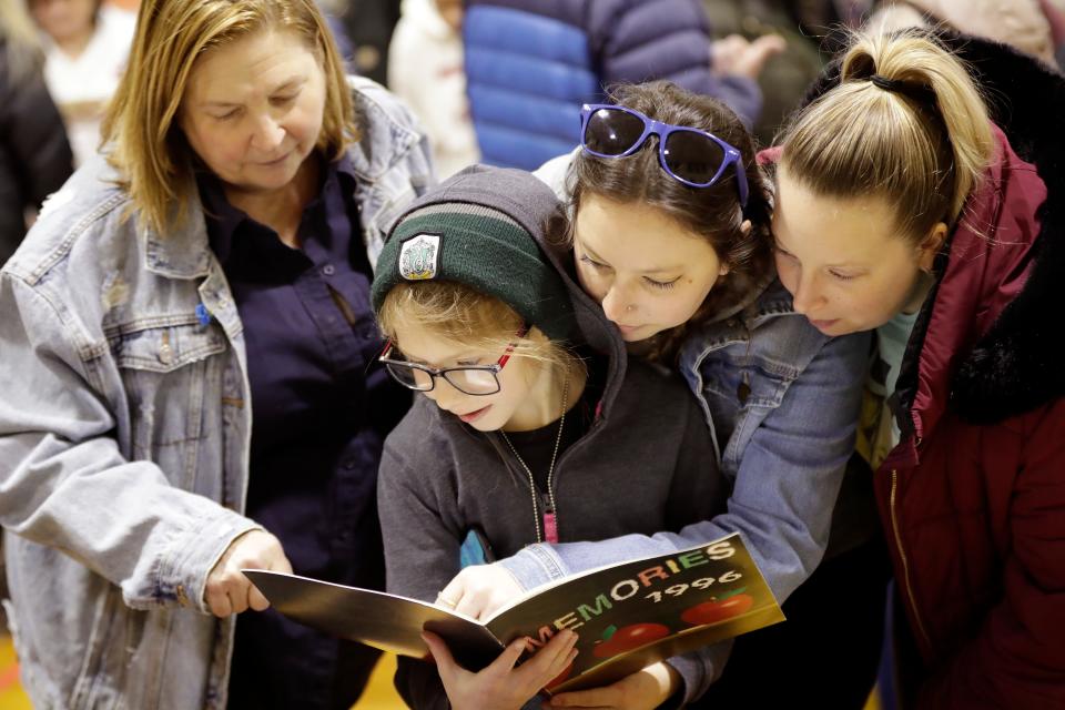 Marie Polar, left, looks through an old yearbook with her daughters Kim Workman and Charlotte Polar, right, along with her granddaughter Mia Workman, 9, during an open house at Roosevelt Elementary School on March 19.