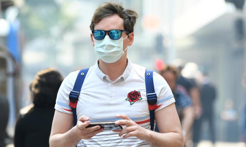 A man seen wearing a dust mask as smoke haze from bushfires in New South Wales blankets the CBD in Sydney on Tuesday.