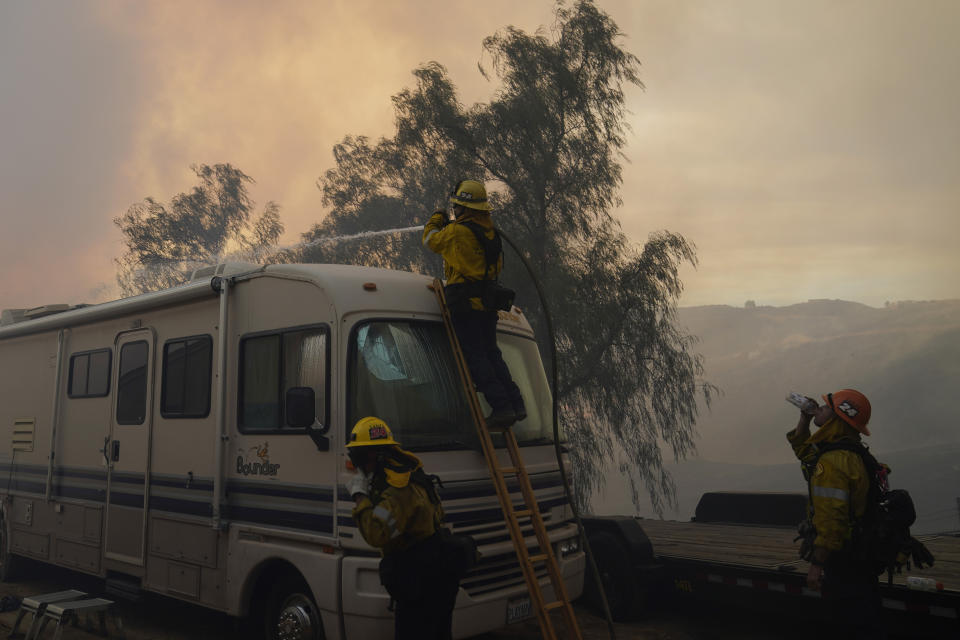 Firefighters pour water over a camper while battling the Route Fire Wednesday, Aug. 31, 2022, in Castaic, Calif. (AP Photo/Marcio Jose Sanchez)