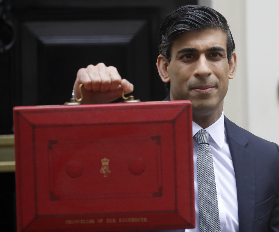 Britain's Chancellor Rishi Sunak stands with his red briefcase in front of 11 Downing Street in London, Wednesday, March 3, 2021. Sunak is expected to announce billions of pounds in tax cuts and spending increases to help workers and businesses hit by the coronavirus pandemic when he delivers his budget to Parliament on Wednesday. (AP Photo/Kirsty Wigglesworth)