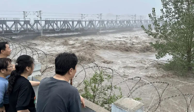 ▲北京市自7月29日起遭連續暴雨侵襲，洪災期間卻有部分居民在岸邊撈物資，甚至拍片轉播打撈實況。（圖／美聯社／達志影像）