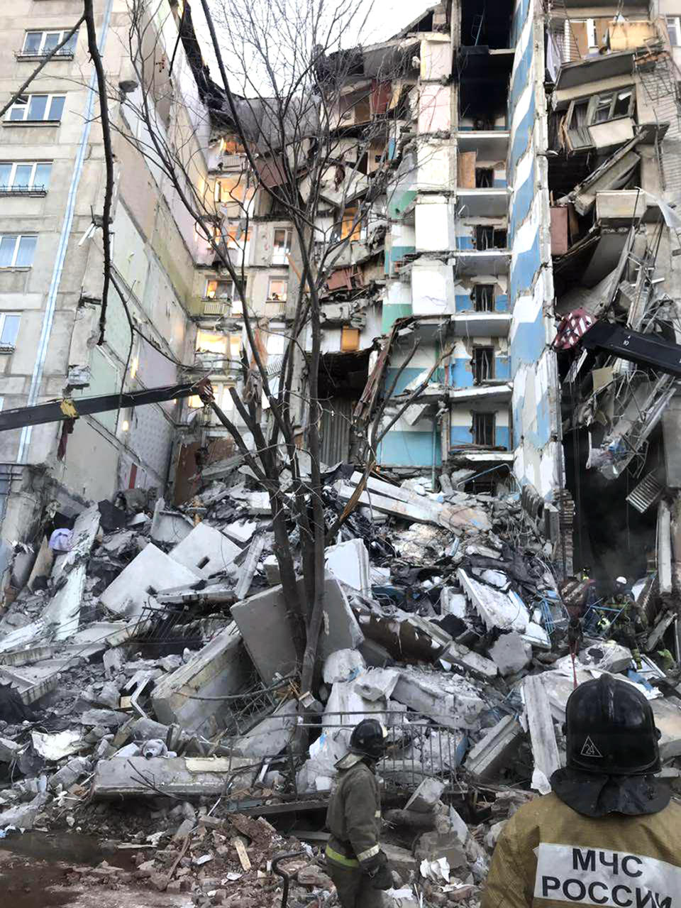 This image provided by the Russian Emergency Situations Ministry taken from tv footage, shows Emergency Situations employees working at the scene of a collapsed section of an apartment building in Magnitogorsk, a city of 400,000 about 1,400 kilometers (870 miles) southeast of Moscow, Russia, Monday, Dec. 31, 2018. Russian emergency officials say that at least four people have died after sections of an apartment building collapsed after an apparent gas explosion in the Ural Mountains region. (Chelyabinsk Region Governor Press Service photo via AP)