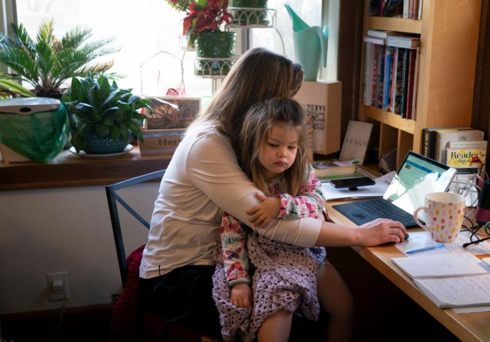 April 1: High School teacher Emily Olin holds her three-year-old daughter Genevieve on her lap as she taught her classes from her home in Minneapolis, Minnesota. (Getty Images)