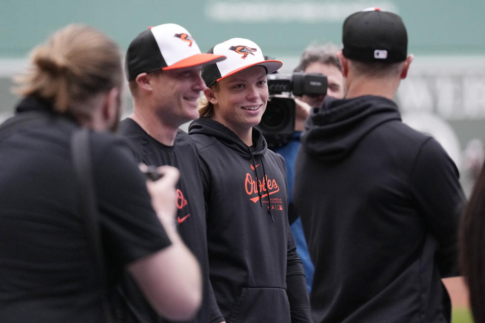 Baltimore Orioles' Jackson Holliday, second from right, smiles while surrounded by cameras and teammates during batting practice prior to his first major league baseball game against the Boston Red Sox, Wednesday, April 10, 2024, in Boston. Holliday, the son of seven-time All-Star Matt Holliday, is schedule to play second base in Wednesday game. (AP Photo/Charles Krupa)