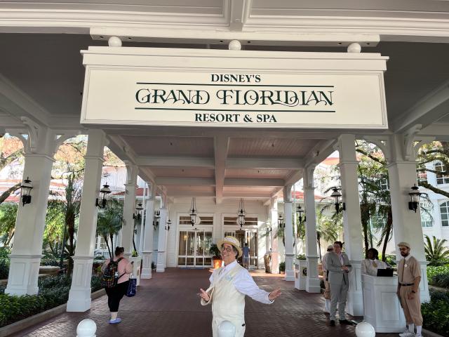 disney cast memeber randy posing for a photo under the grand floridian entrance sign at the front door of the resort
