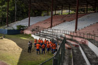 Cuban coaches dressed in orange, prepare a training session with the assistance of two foreign coaches dressed in gray, at the Pedro Marrero stadium in Havana, Cuba, Wednesday, Sept. 14, 2022. This initial group of 16 coaches was recently trained by international FIFA officials with the aim to create Cuba's next generation of professional soccer players on an island long known for birthing baseball and boxing superstars. (AP Photo/Ramon Espinosa)