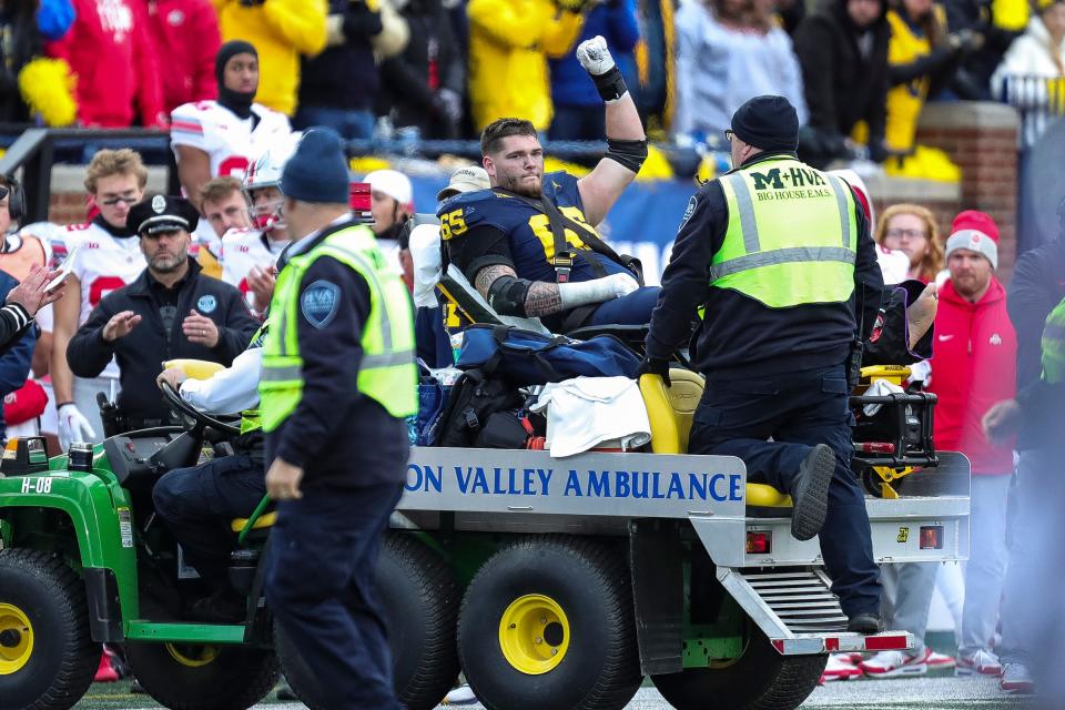 Michigan offensive lineman Zak Zinter waves to the crowd as he is carted off the field due to a lower-leg injury during the second half against Ohio State at Michigan Stadium in Ann Arbor on Saturday, Nov. 25, 2023.