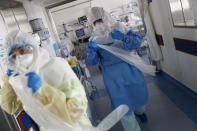 Nurses put on medical aprons before tending to a patient inside a COVID-19 ICU at Santa Maria hospital in Lisbon, Friday, Oct. 30, 2020. Portugal is reporting a record number of new COVID-19 cases, deaths and hospital admissions. (AP Photo/Armando Franca)