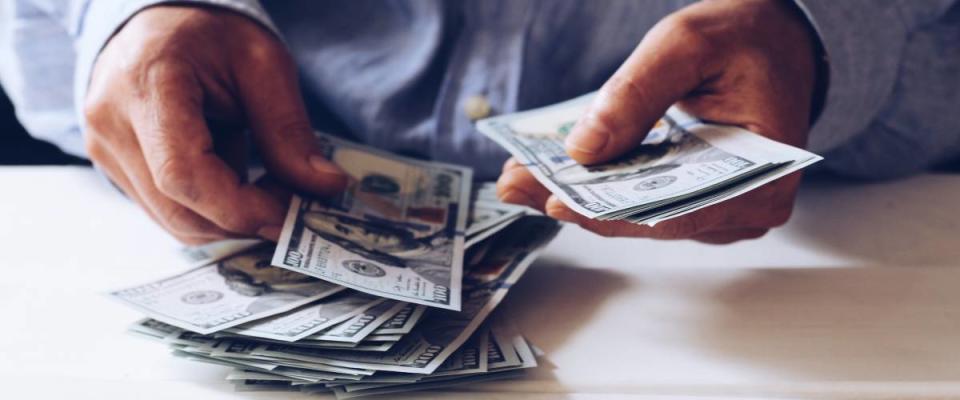 Close up of person counting out cash.