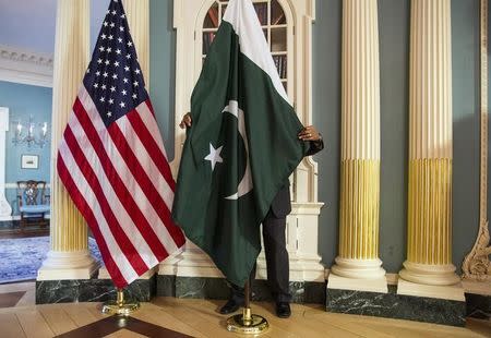 A State Department contractor adjust a Pakistan national flag before a meeting between U.S. Secretary of State John Kerry and Pakistan's Interior Minister Chaudhry Nisar Ali Khan on the sidelines of the White House Summit on Countering Violent Extremism at the State Department in Washington February 19, 2015. REUTERS/Joshua Roberts