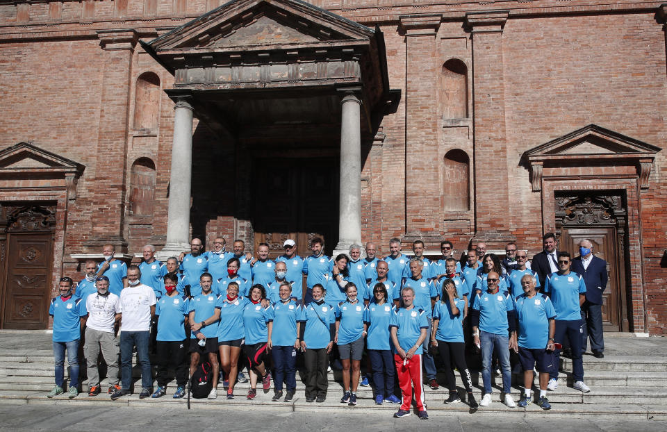 Runners pose prior to the start of a 180-kilometer relay race, in Codogno, Italy, Saturday, Sept. 26, 2020. Italy’s coronavirus Patient No. 1, whose case confirmed one of the world’s deadliest outbreaks was underway, is taking part in a 180-kilometer relay race as a sign of hope for COVID victims after he himself recovered from weeks in intensive care. Mattia Maestri, a 38-year-old Unilever manager, was suited up Saturday for the start of the two-day race between Italy’s first two virus hotspots. It began in Codogno, where Maestri tested positive Feb. 21, and was ending Sunday in Vo’Euganeo, where Italy’s first official COVID death was recorded the same day. (AP Photo/Antonio Calanni)