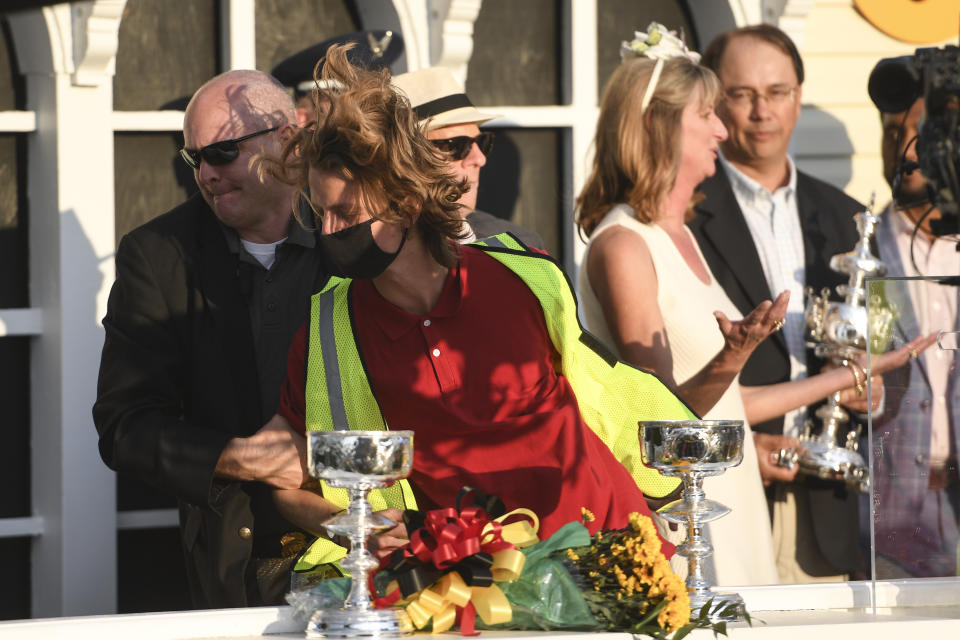 Security removes a protester, in red shirt, after he reached the stage during the trophy presentation after Flavien Prat atop Rombauer won the 146th Preakness Stakes horse race at Pimlico Race Course, Saturday, May 15, 2021, in Baltimore. (AP Photo/Will Newton)