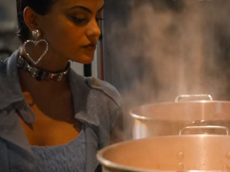 drea looking into big pots of food in do revenge