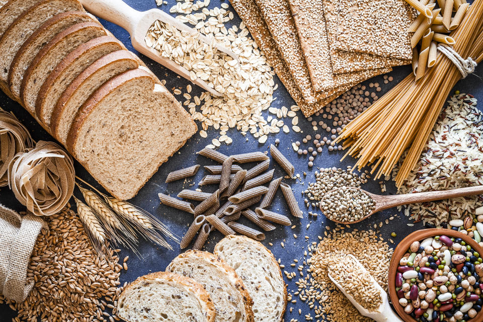 Top view of wholegrain and cereal composition shot on rustic wooden table. This type of food is rich of fiber and is ideal for dieting. The composition includes wholegrain sliced bread, wholegrain pasta, oat flakes, flax seed, brown rice, mixed beans, wholegrain crackers and spelt. Predominant color is brown. DSRL studio photo taken with Canon EOS 5D Mk II and Canon EF 100mm f/2.8L Macro IS USM