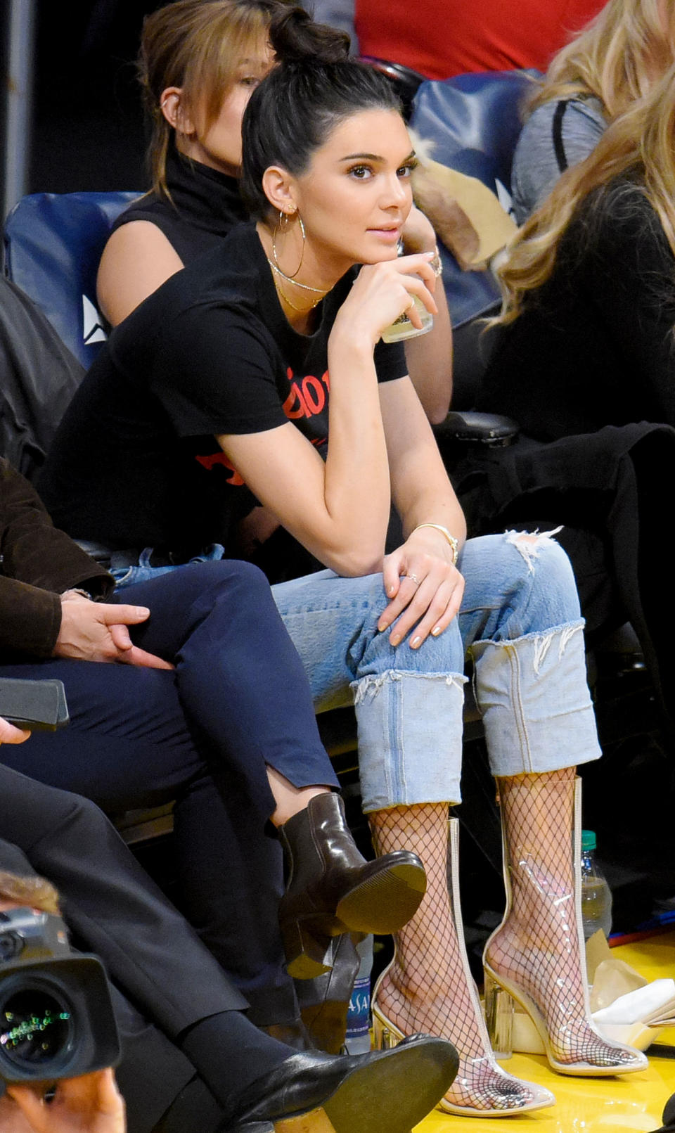 <p>Jenner sat courtside in clear Ego ankle boots (shop a similar style here: $48; <a rel="nofollow noopener" href="http://www.anrdoezrs.net/links/7799179/type/dlg/sid/IScelebclearshoes/http://www.forever21.com/Product/Product.aspx?br=F21&category=branded-shop&productid=2000055447" target="_blank" data-ylk="slk:forever21.com;elm:context_link;itc:0;sec:content-canvas" class="link ">forever21.com</a>), which she expertly paired with fishnet stockings and cropped straight-leg jeans. </p>