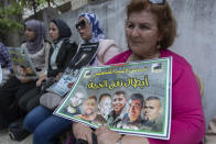 A Palestinian woman carries a poster with pictures of the six Palestinian prisoners who escaped from an Israeli jail that says "heroes of the freedom tunnel," during a protest in the West Bank city of Ramallah, Tuesday, Sept. 14, 2021. The cinematic escape of six prisoners who tunneled out of an Israeli penitentiary shone a light on Israel's mass incarceration of Palestinians, one of the many bitter fruits of the conflict. (AP Photo/Nasser Nasser)