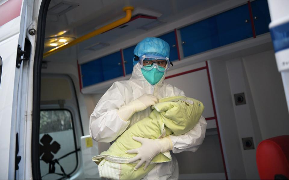 A medical worker holds the baby girl born by a woman infected with novel coronavirus in an ambulance at the Second Affiliated Hospital of Xi'an Jiaotong University in Xi'an, China - Xinhua/REX