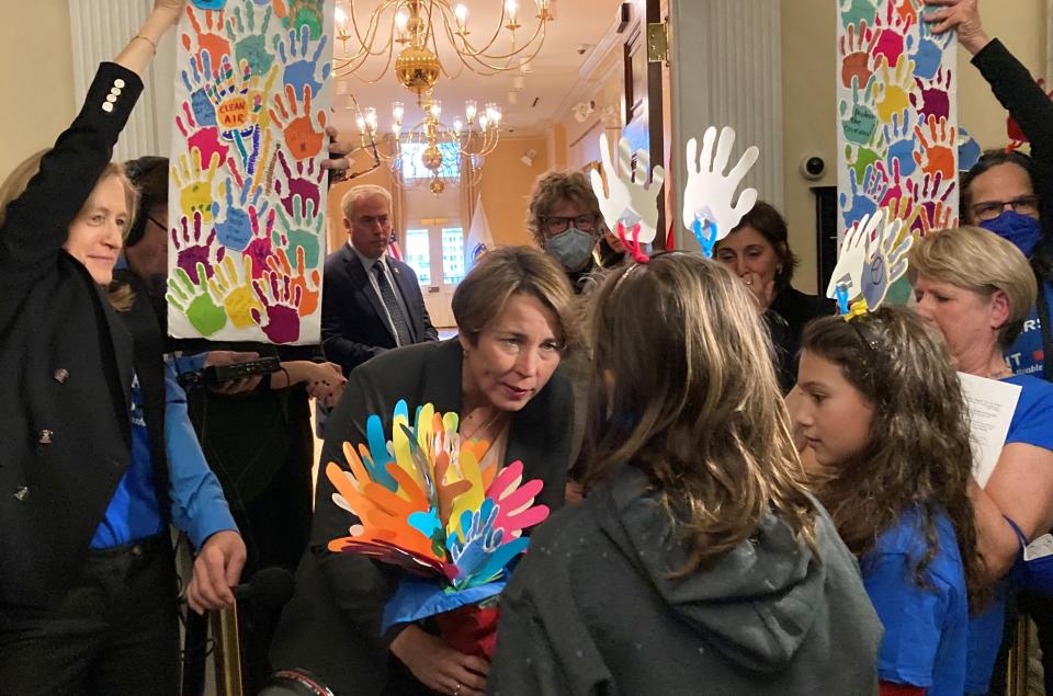 Gov. Maura Healey accepts a bouquet of hands from young climate activists who visited the Statehouse Wednesday with their parents to show their support of stated climate goals.