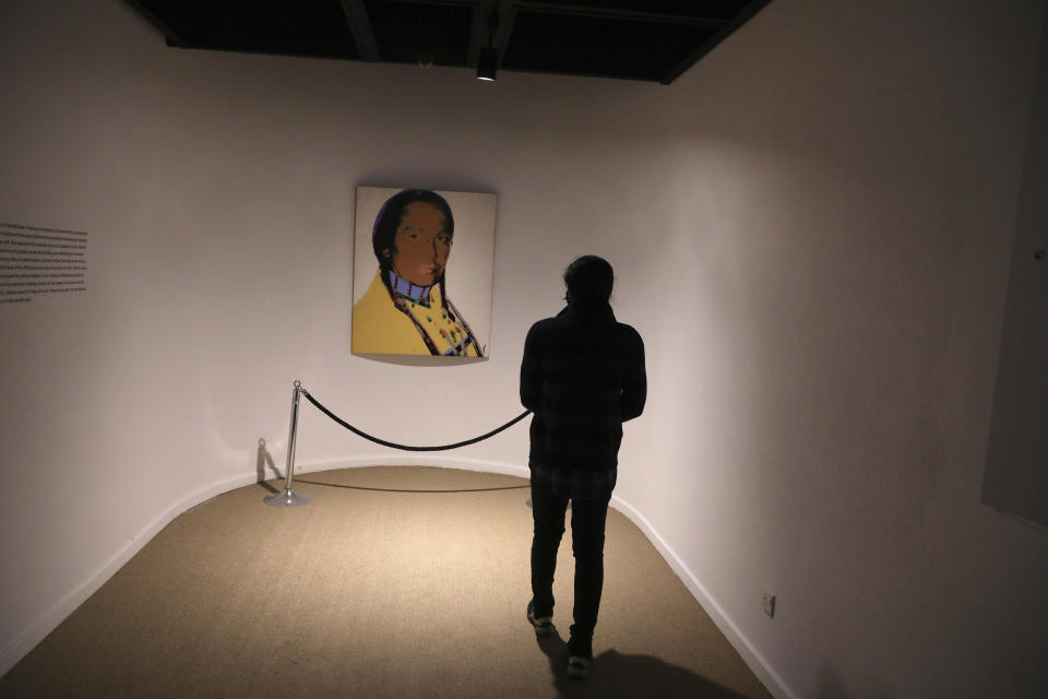 A visitor looks at portrait of the leader of the American Indian Movement Russel Means by American artist Andy Warhol at Tehran Museum of Contemporary Art in Tehran, Iran on Oct. 19, 2021. Iranians are flocking to Tehran's contemporary art museum to marvel at American pop artist Andy Warhol’s iconic work. (AP Photo/Vahid Salemi)