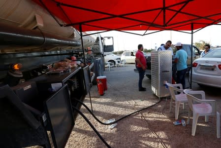 Men fill their cars with fuel from Brega in Tripoli