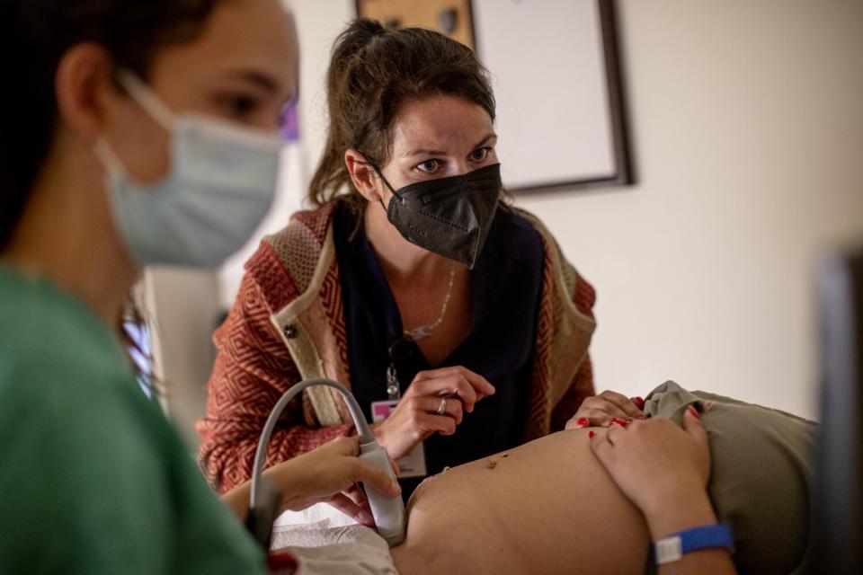 Two people performing an ultrasound on a woman