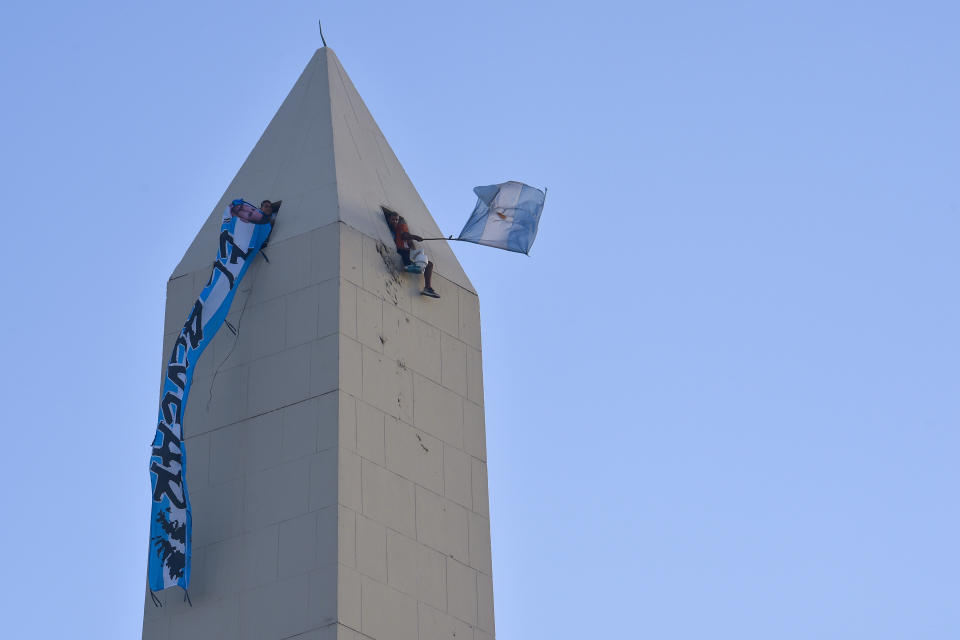 Soccer fans wave flags from the Obelisk monument as they wait to see the Argentine soccer team that won the World Cup, in Buenos Aires, Argentina, Tuesday, Dec. 20, 2022. (AP Photo/Gustavo Garello)