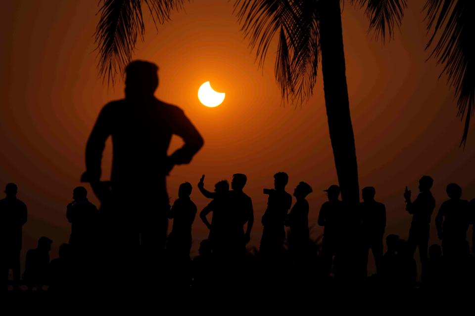 People watch a partial solar eclipse in Mumbai, India, Tuesday, Oct. 25, 2022. (AP Photo/Rajanish Kakade) ORG XMIT: MUM102