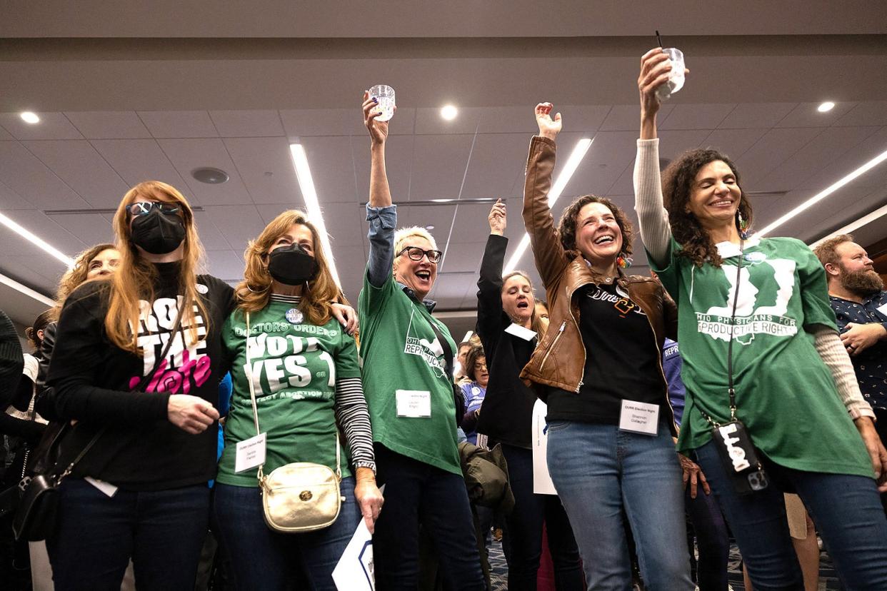 Abortion rights supporters celebrate with drinks raised in the air.