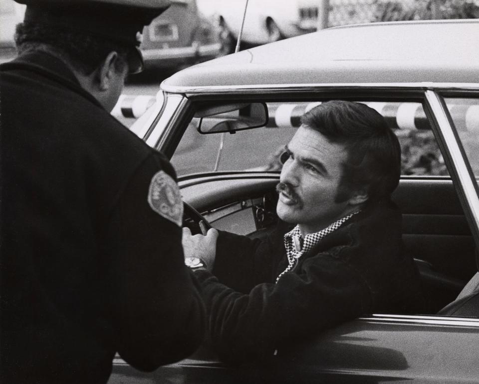 <p>A police officer stop Reynolds outside of CBS Studios in 1972. The actor had just wrapped the TV series <em>Dan August </em>for the studio. </p>