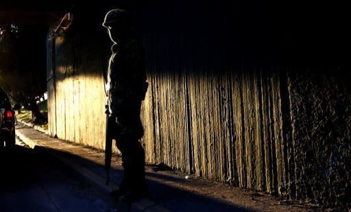 A soldier stands guard on Lazaro Cardenas Avenue in Guadalajara where three trucks with 26 corpses inside were found early morning, November 24. Fifty dead bodies have been discovered over the past two days in western Mexico, victims of a fierce war waged between the government and the nation's powerful drug cartels