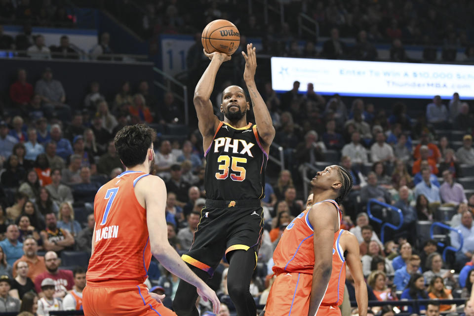 Phoenix Suns forward Kevin Durant, middle, shoots over Oklahoma City Thunder forwards Chet Holmgren, left, and Jalen Williams during the first half of an NBA basketball game Friday, March 29, 2024, in Oklahoma City. (AP Photo/Kyle Phillips)