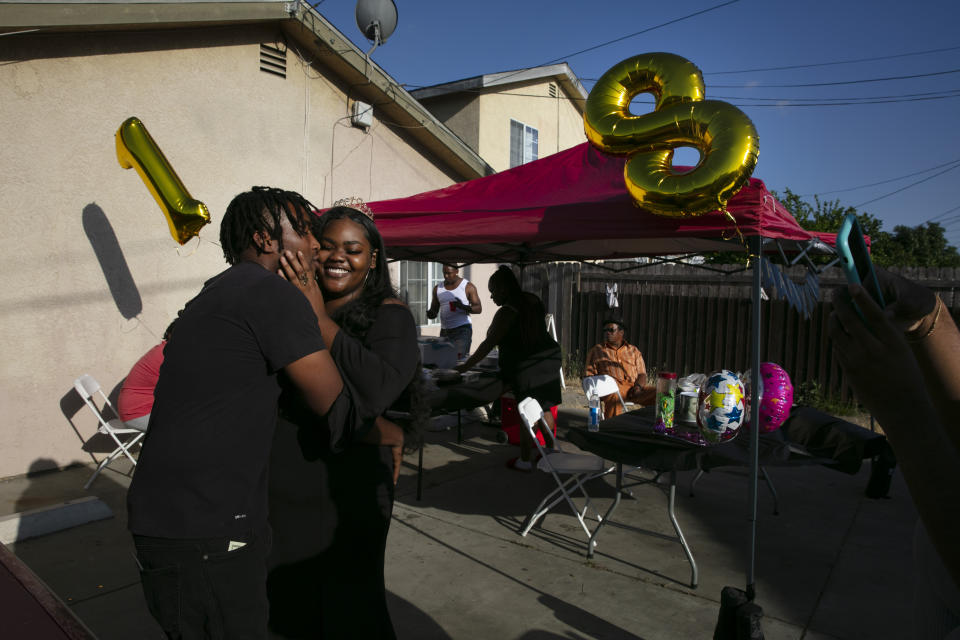 Kyaira Shaw gets a kiss from her boyfriend, Camari Baseer, left, while posing for photos at her 18th birthday party in the Watts neighborhood of Los Angeles, Wednesday, June 17, 2020. (AP Photo/Jae C. Hong)