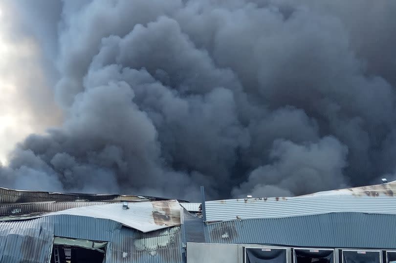 The scene of the aftermath of the fire in Cannock, where the gutted shell of an industrial building remains. Thick smoke can be seen billowing into the sky. -Credit:Richard Pursehouse