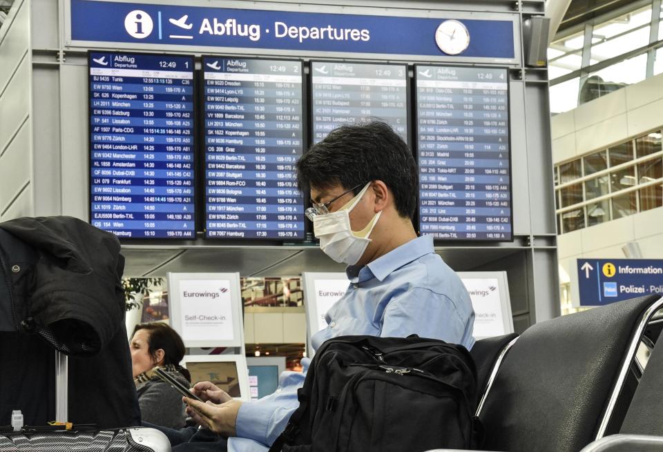 FILE - A passenger with a face mask waits for his flight at the airport in Duesseldorf, Germany, Thursday, March 19, 2020. The European Union Aviation Safety Agency said Wednesday that from next week onward it is no longer recommending the use of medical masks at airports and on planes due to the coronavirus. (AP Photo/Martin Meissner, File)