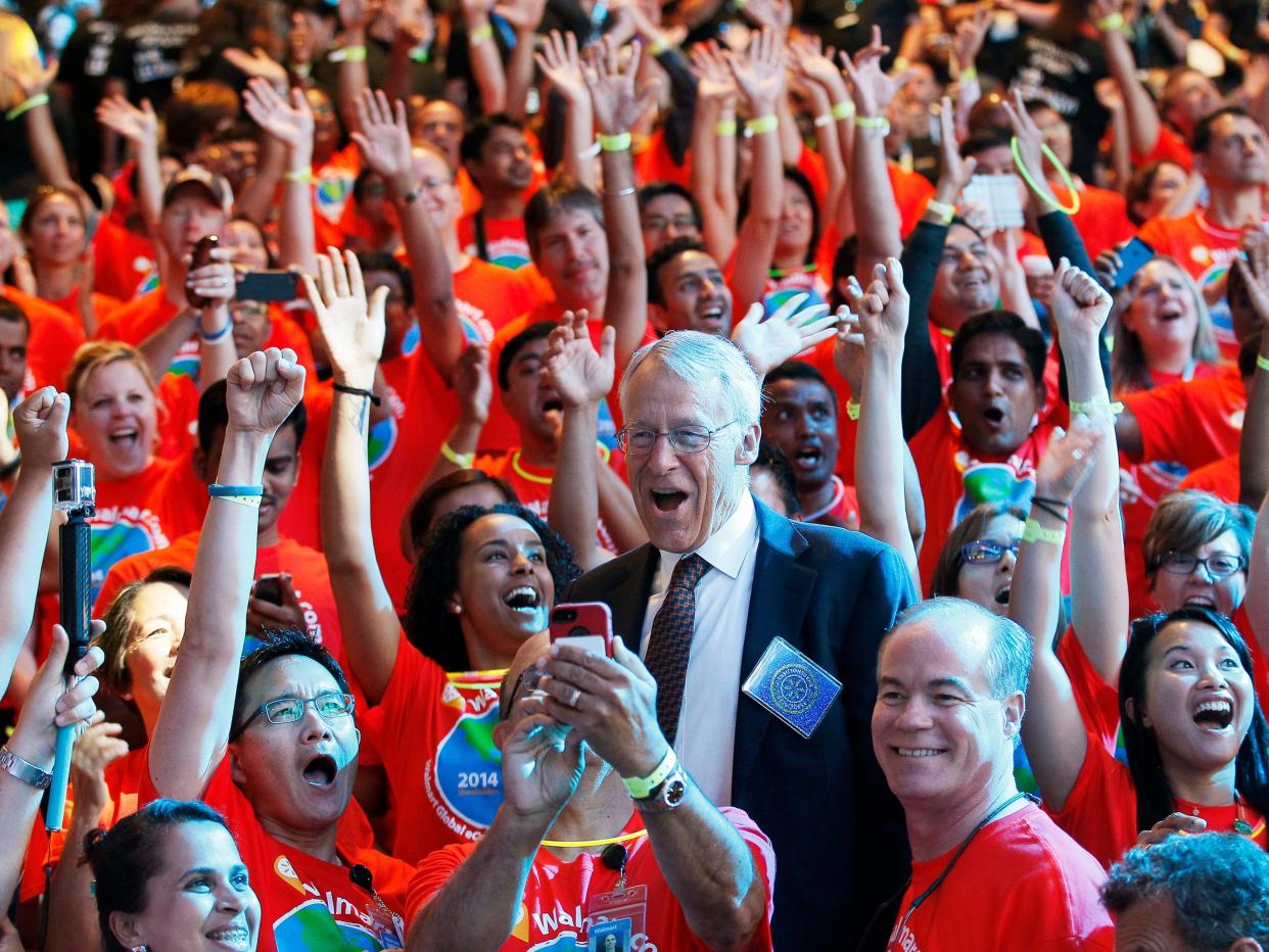 Rob Walton standing amid cheering Walmart employees wearing red shirts